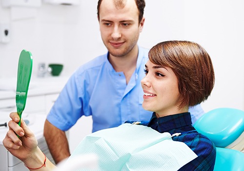 Dental patient looking at her mouth in a mirror