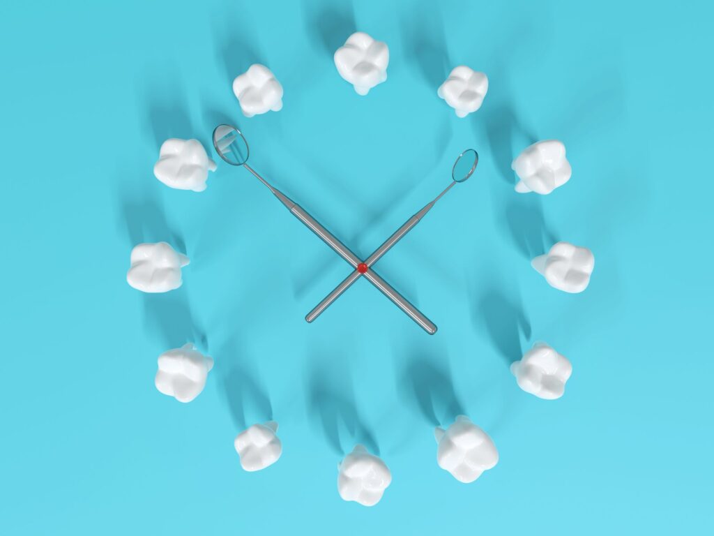 Bird's eye view of 12 teeth arranged like a clock with dental mirrors as hands